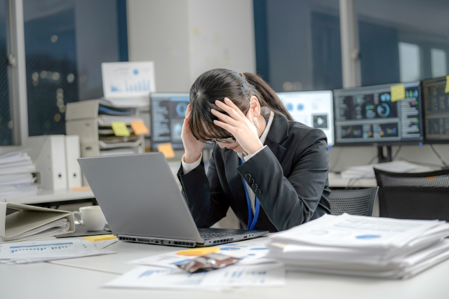 デスクワークで疲労する女性